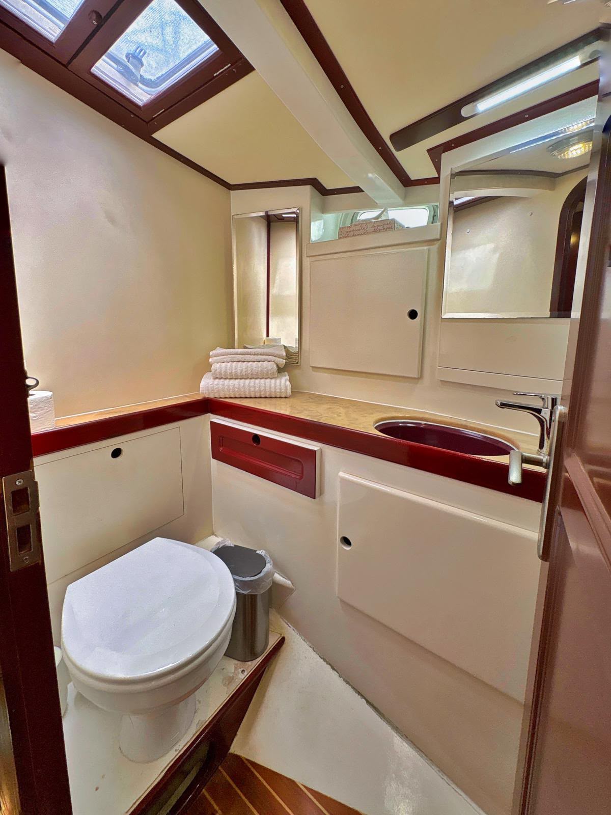 Baño de proa con lavabo, espejo y toallas preparadas